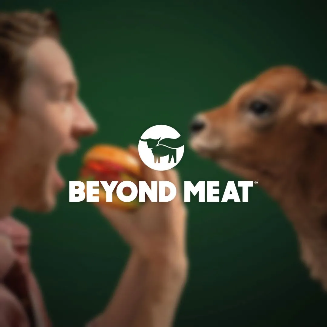 Brand Kampagne für Beyond Meat: ein Mann beißt in einen Beyond Burger, ihm gegenüber steht ein Kalb